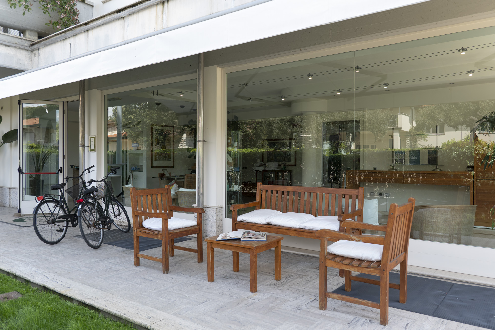 Area comune al piano terra con tavoli e biciclette nel verde